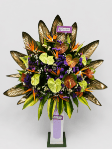 Elegante base de pie elaborada con anturios, aves del paraíso, rusco, hojas de ave del paraíso y estatis. Un arreglo floral tropical de gran impacto, ideal para inauguraciones, eventos corporativos, lanzamientos, hoteles y celebraciones especiales.