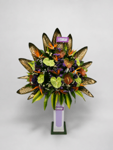 Elegante base de pie elaborada con anturios, aves del paraíso, rusco, hojas de ave del paraíso y estatis. Un arreglo floral tropical de gran impacto, ideal para inauguraciones, eventos corporativos, lanzamientos, hoteles y celebraciones especiales.