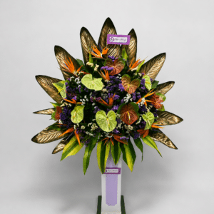 Elegante base de pie elaborada con anturios, aves del paraíso, rusco, hojas de ave del paraíso y estatis. Un arreglo floral tropical de gran impacto, ideal para inauguraciones, eventos corporativos, lanzamientos, hoteles y celebraciones especiales.