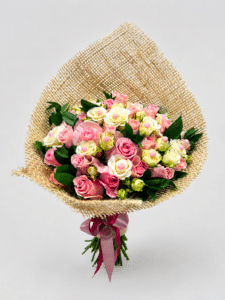 Elegante bouquet Romance elaborado con rosas, rosa spray y rusco, decorado con delicadas perlas y presentado en una envoltura de fique con moño. Un detalle romántico, natural y sofisticado para sorprender.
