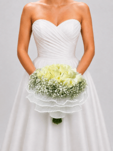 Elegante yugo floral elaborado con rosas y delicada gypsophila, acompañado de una sofisticada entretela perlada que aporta textura y luminosidad. Un diseño romántico para realzar la decoración de tu boda.