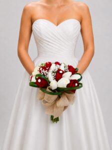 Elegante yugo nupcial elaborado con rosas rojas y blancas, delicada gypsophila, perlas y cinta decorativa. Una composición romántica y sofisticada para realzar la decoración de tu ceremonia.