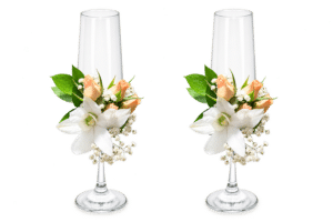 Delicada decoración floral para copas nupciales, elaborada con orquídeas, rosa spray, rusco y gypsophila. Una composición elegante y romántica para acompañar uno de los momentos más especiales de la celebración.