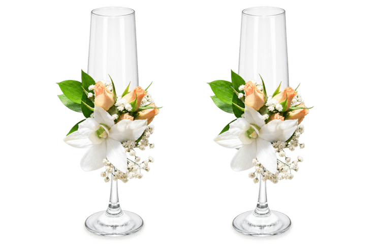 Delicada decoración floral para copas nupciales, elaborada con orquídeas, rosa spray, rusco y gypsophila. Una composición elegante y romántica para acompañar uno de los momentos más especiales de la celebración.